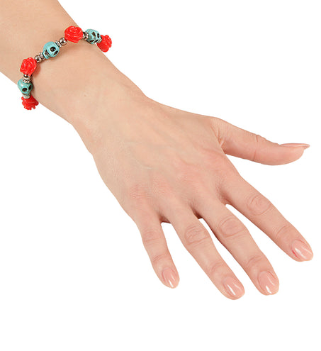 Armband met schedels en rozen om de arm gedragen, rode roosjes en blauwe schedelkralen zichtbaar