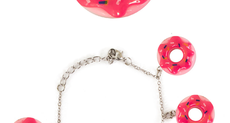 Armband donut roze met zeven donutbedels aan een zilverkleurige schakelketting voor een themafeest