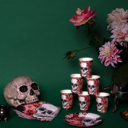 Bekertjes Day of the Dead opgestapeld op een halloweentafel met decoratieschedel en bloemen