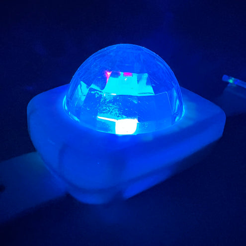 Blauw oplichtende koepel van de lichtgevende armband, zijaanzicht in het donker