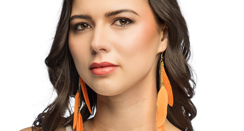 Boho verenoorbellen oranje gedragen bij los donker haar en een wit gehaakt topje, voor een hippiefeest
