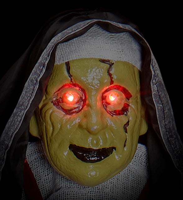 Detail van het groengele nonnenmasker met gescheurde huid en rood oplichtende ogen