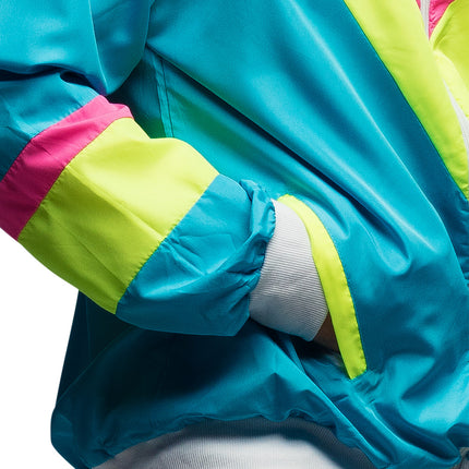 Detail van het neonblauwe trainingsjasje: glanzende polyester mouw met neongele en roze band en wit geribd boord
