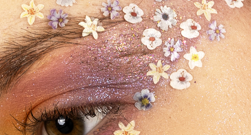 Gedroogde bloemetjes in wax in wit en paars als eyedesign rond het oog, over paarse schmink