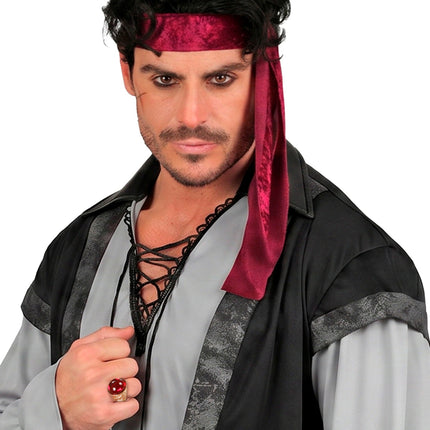 Gouden ring met rode steen aan de hand van een heer in piratenoutfit