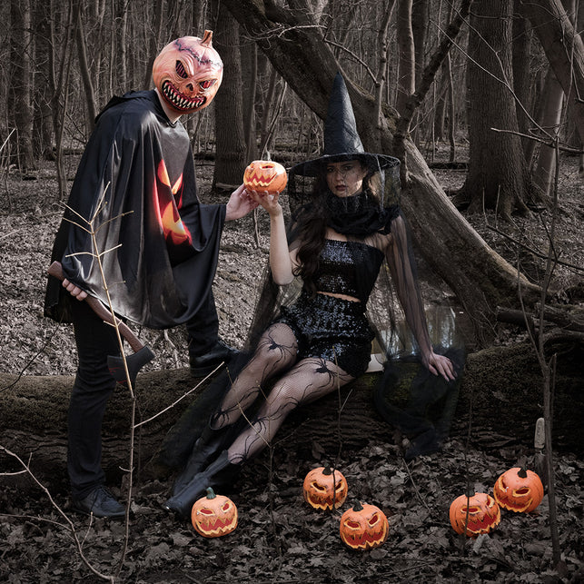 Hoofdmasker Pumpkin monster gedragen met zwarte cape in een herfstbos tijdens Halloween