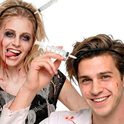 Injectienaald door hoofd gedragen door zombiepaar met bloedschmink tijdens Halloween