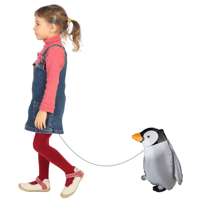 Kind laat de folieballon wandelende pinguin aan een koordje meelopen op een kinderfeestje