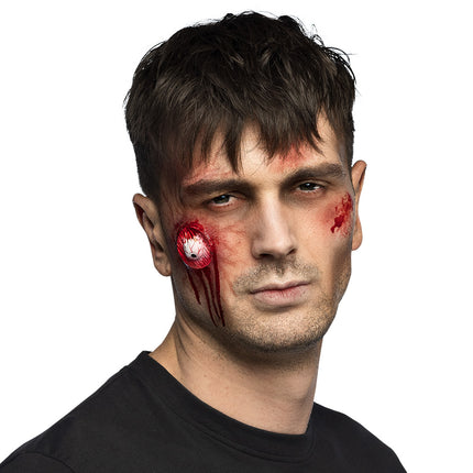 Latex wond met oogbalmotief op de wang met rode bloeddruppels, zombielook voor Halloween