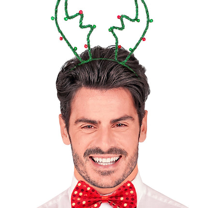 Man met groen rendiergewei op zijn hoofd en rode vlinderdas op een kerstfeest
