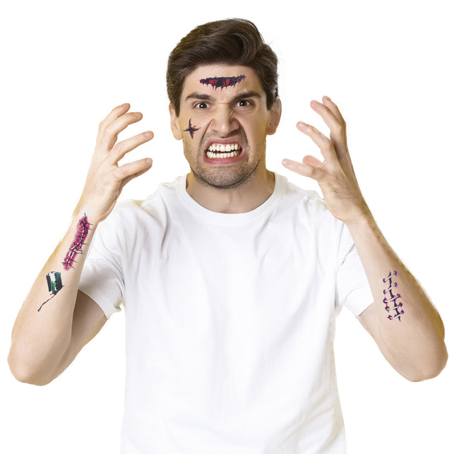 Man met nepwondtattoos op voorhoofd, wang en armen bij een wit shirt voor een zombielook