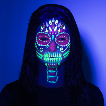Neon doodskop geschminkt met de Bright skull UV set, oplichtende lijnen onder blacklight voor Halloween