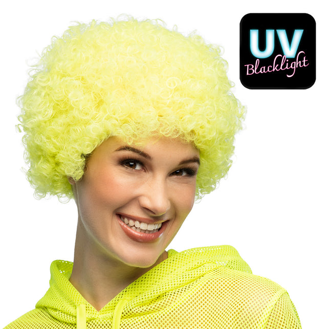 Neongele afropruik met UV-effect, gedragen door vrouw met geel nethemd, voor neonparty