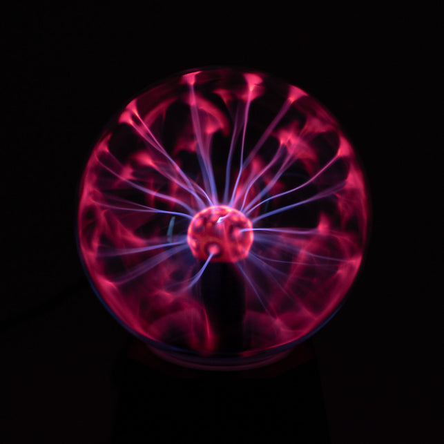 Plasmalamp met roze en violette lichtbogen in de glazen bol, oplichtend in het donker