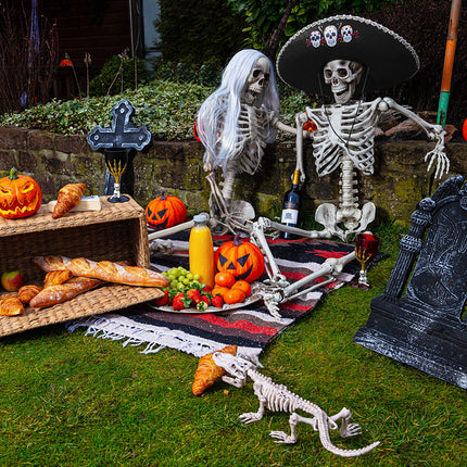 Plastic kelk Skull claw zwart met rode drank tussen pompoenen, skeletten en een grafsteen voor Halloween