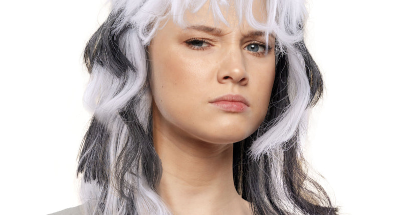 Pruik wit-zwart schouderlang met warrige laagjes en volle witte pony, gedragen op een themafeest