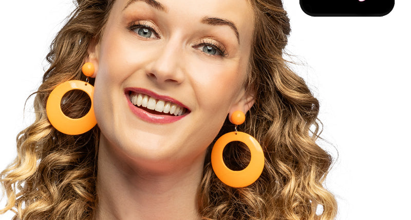 Retro oorbellen neonoranje met grote ronde hanger gedragen door een vrouw met lange krullen, voor een neon party