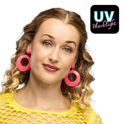 Retro oorbellen neonroze met open ronde hangers gedragen bij een geel netshirt voor een jaren 80-feest