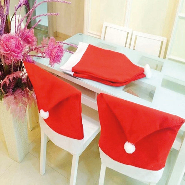 Rode kerstmuts stoelhoezen op witte stoelen, met opgevouwen exemplaren op de eettafel