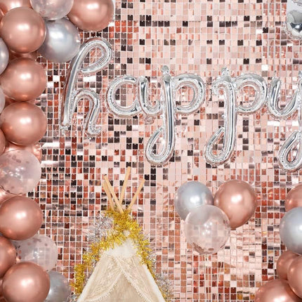 Roségouden fotowand van folie plaatjes met ballonboog en letterballon bij een verjaardag of babyshower