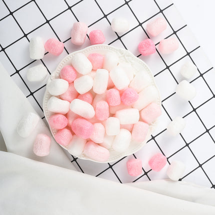Roze en witte foam vlokjes als ballonvulling op een wit schaaltje voor feestdecoratie