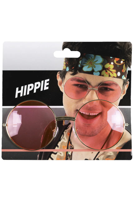 Uilebril goud met grote ronde roze glazen, gedragen bij een hippielook met gebloemde hoofdband