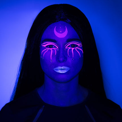 UV schminkset heks onder blacklight: paars gezicht, roze maansikkel, oogpatroon en blauwe lippen voor Halloween