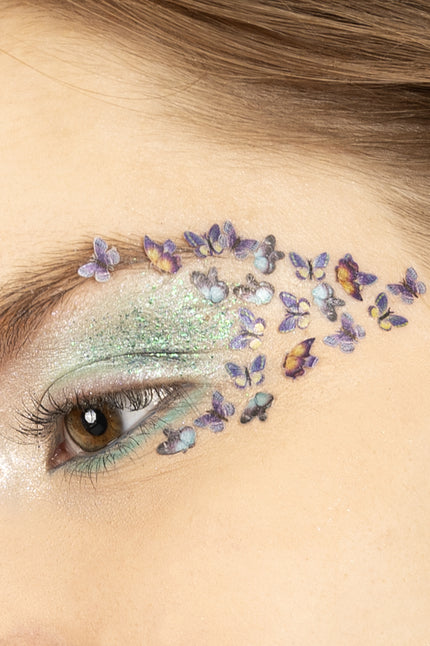 Vlinderglitters in wax op het ooglid, paarse en gele vlindertjes uitlopend naar de slaap voor een themafeest