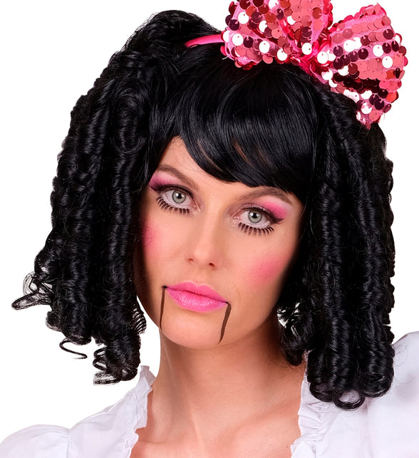 Zwarte pruik speelgoed pop gedragen met een roze strik bij een poppenlook